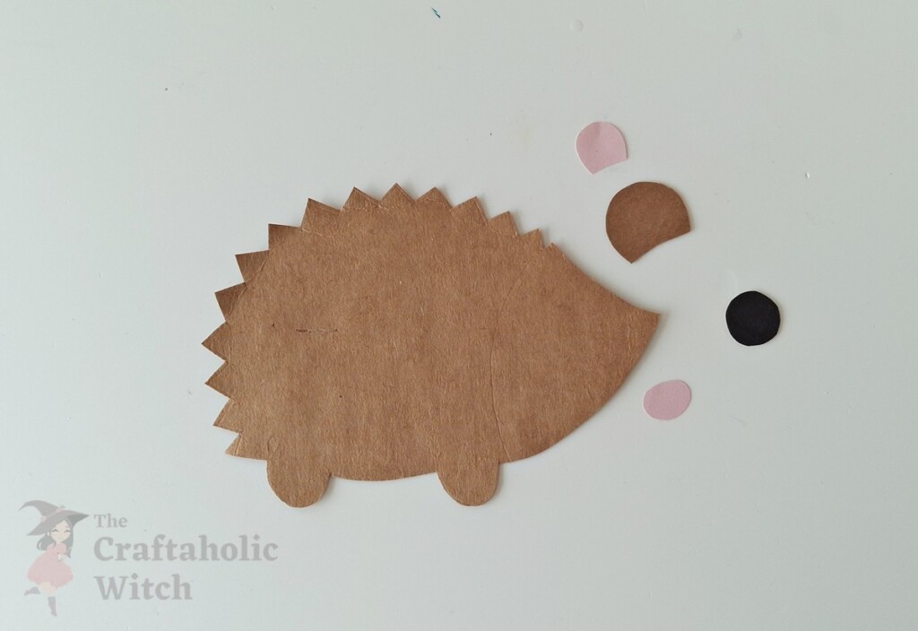 Step 1 of cardstock hedgehog craft showing cut brown cardstock base with zigzag edges and facial feature pieces