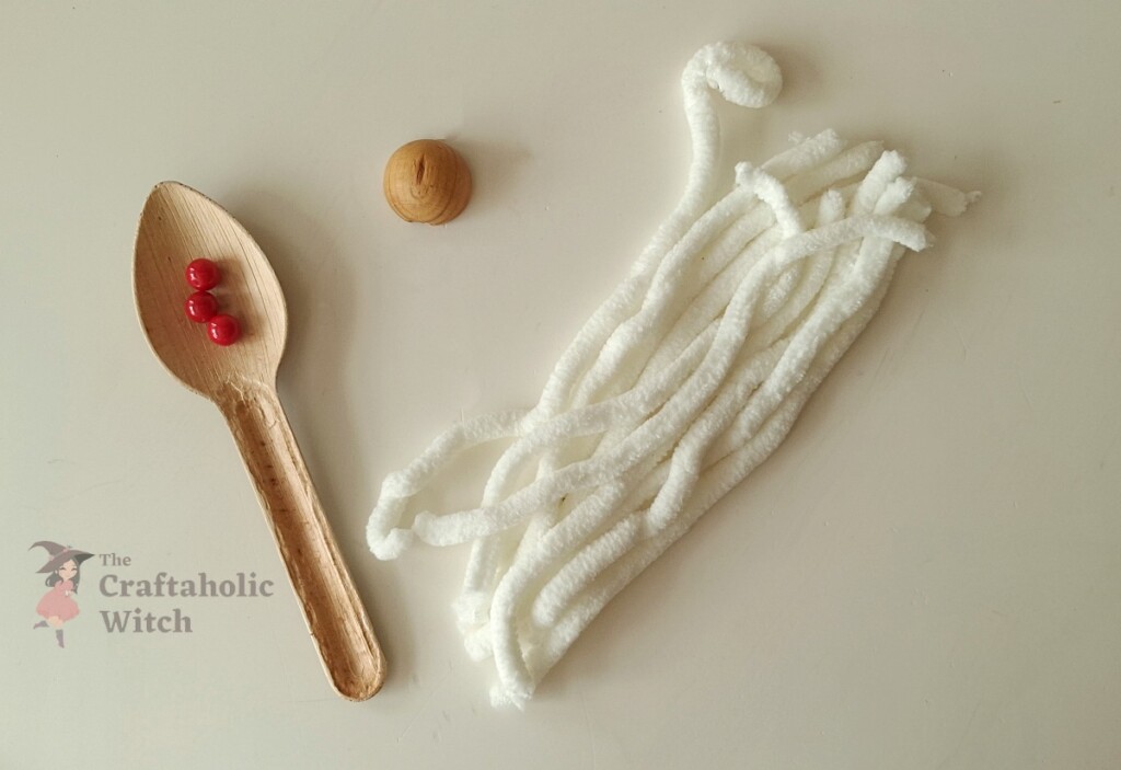 Christmas gnome craft supplies including red beads, wooden bead nose, and yarn pieces for beard